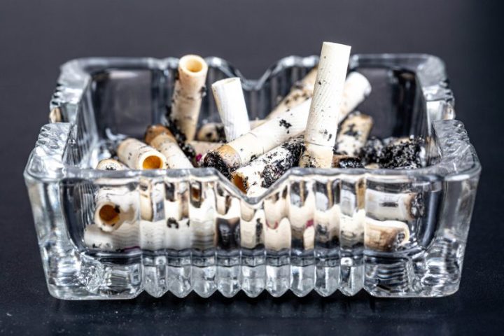A glass ashtray full of used cigarette buts.