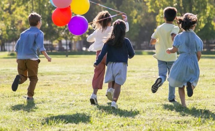 Children running with balloons, facing away from camera.